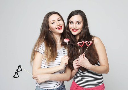 Photo for Funny girls, two young female friends, ready for party, portrait over grey background - Royalty Free Image