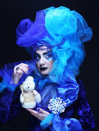 Photo for Young beautiful woman with creative visage and costume holding toy bear over black background. Close up. Party concept. - Royalty Free Image