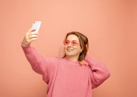 Photo for Image of cheerful curvy woman standing isolated over pink background wall talking by mobile phone. - Royalty Free Image