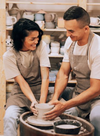Téléchargez les photos : Couple amoureux travaillant ensemble sur une roue de potier dans un atelier d'artisanat. Style de vie et concept de passe-temps. - en image libre de droit