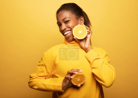 Photo for Young happy afro american woman hold orange slices look amazed isolated on yellow color background. - Royalty Free Image