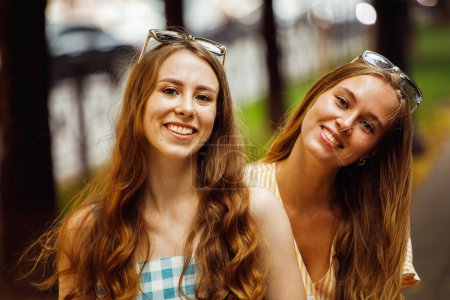 Téléchargez les photos : Inspiré dames riantes posant ensemble sur fond de ciel. Photo extérieure de sœurs caucasiennes intéressées profitant d'une bonne journée. - en image libre de droit