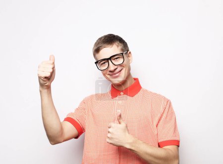 Téléchargez les photos : Jeune homme portant des lunettes montrant ok sur fond blanc - en image libre de droit