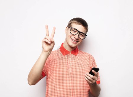 Photo for Happy young man in shirt gesturing and smiling while talking on the mobile phone over white background - Royalty Free Image