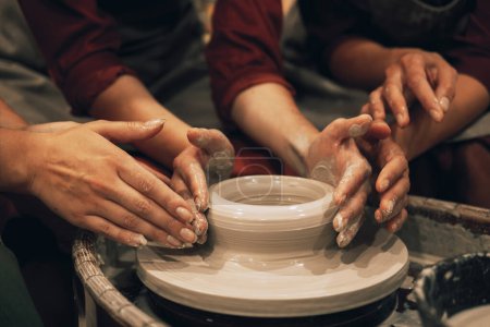 Téléchargez les photos : Trois femmes travaillent sur une roue de potiers, faisant un vase. Le concept d'amitié, de passe-temps et de créativité. - en image libre de droit