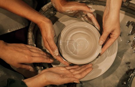 Foto de Tres mujeres están trabajando en una rueda de alfarero, haciendo un jarrón. El concepto de amistad, aficiones y creatividad. - Imagen libre de derechos