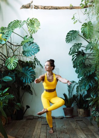 Téléchargez les photos : Femme adulte pratique le yoga dans la jungle urbaine. Femme en yoga asanas et Pilates à la maison. Concept de style de vie. - en image libre de droit