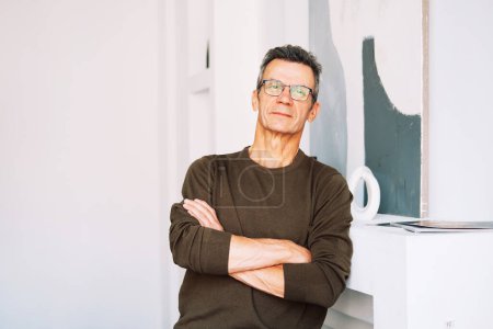 Photo for Handsome middle aged 60s single man looking at camera standing at home, satisfied confident senior mature european male model posing indoors with crossed arms. - Royalty Free Image