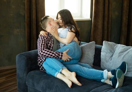 Photo for Young beautiful couple is sitting on the couch and hugging. Happy family life. Love. - Royalty Free Image