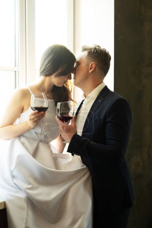 Foto de La novia y el novio sostienen en sus manos vasos con vino. Joven y feliz. - Imagen libre de derechos