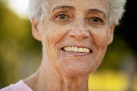 Photo for Portrait of smiling elderly woman at park. Close up portrait. Happy thoughful mature woman relaxing outdoor. - Royalty Free Image