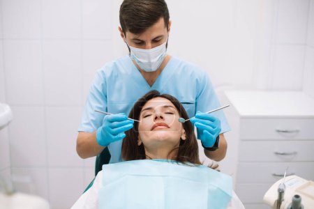 Photo for Young male dentist making treatment in modern clinic - Royalty Free Image