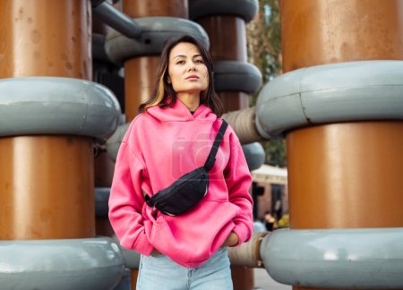 Téléchargez les photos : Belle jeune femme asiatique élégante en sweat-shirt rose et jeans posant tout en regardant la caméra, concept de style de vie. - en image libre de droit