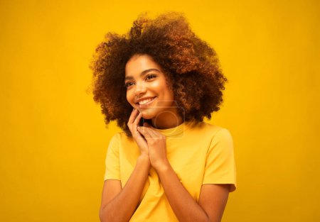Téléchargez les photos : Style de vie, émotion et concept de personnes : jeune femme afro-américaine souriante sur fond jaune - en image libre de droit