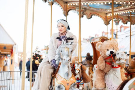 Téléchargez les photos : Belle jeune femme sur un manège. Le modèle est monté sur un cheval et s'amuse pendant les vacances d'hiver. - en image libre de droit