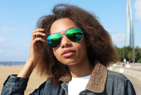 Photo for Young afro woman wearing sunglasses with perfect teeth and dark clean skin having rest outdoors - Royalty Free Image