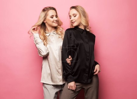 Téléchargez les photos : Deux belles jeunes femmes en vêtements décontractés posant sur fond rose. Concept de mode. - en image libre de droit