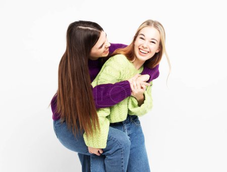 Photo for Laughing two girlfriends hugging and having fun together over white background. - Royalty Free Image