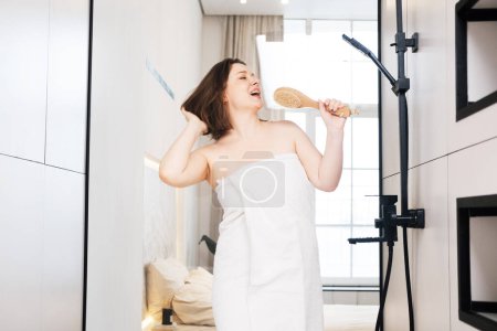 Photo for Cheerful plump woman singing in the shower using a brush as a microphone. Lifestyle concept. - Royalty Free Image