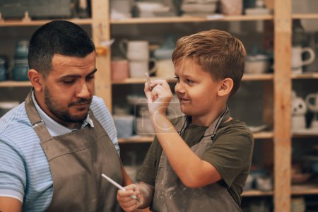 Photo for Dad and little son are engaged in creativity in the pottery workshop. - Royalty Free Image