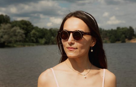 Photo for Beautiful fashionable woman outdoors. Young female model wearing sumglasses posing in summer park. Close up portrait. - Royalty Free Image