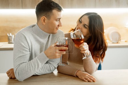 Téléchargez les photos : Jeune couple amoureux de boire du vin rouge dans la cuisine de la maison. Romantique et amour, - en image libre de droit