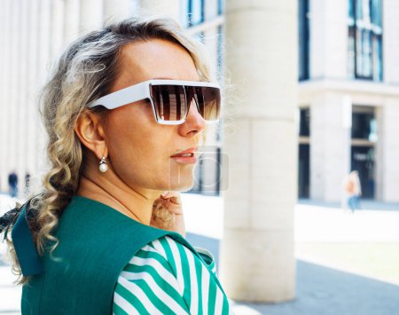 Photo for Portrait of an adult woman with blond curly hair wearing sunglasses. City portrait close up. - Royalty Free Image