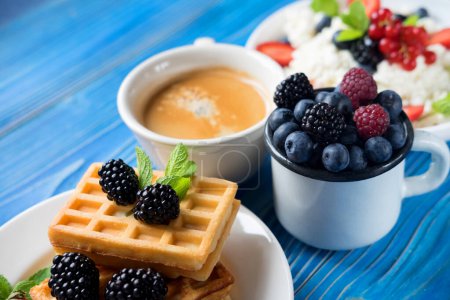 Foto de Buen desayuno para el nuevo día. Gofres de mora con arándanos y una taza de café para el desayuno, de cerca - Imagen libre de derechos