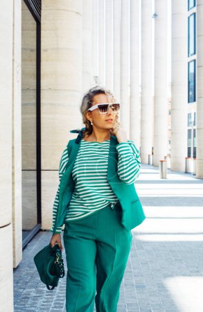 Foto de Una mujer de moda. Modelo pelo rubio viste traje verde con pantalones y accesorios de moda chaqueta. Traje de moda multicapa. Moda, ropa de estilo - Imagen libre de derechos
