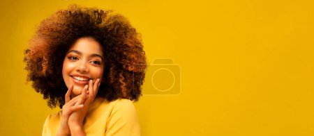 Photo for People, leisure and happiness concept: Charming fashionable young black curly woman 20s wears yellow shirt on yellow background studio portrait - Royalty Free Image