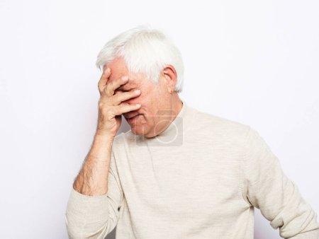 Photo for Dissatisfied elderly man covers his face with his hand, experiences negative emotions, disappointment. Close up. - Royalty Free Image