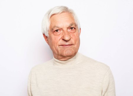 Téléchargez les photos : Homme âgé aux cheveux gris fronce les sourcils et semble mécontent sur fond blanc. Gros plan. - en image libre de droit
