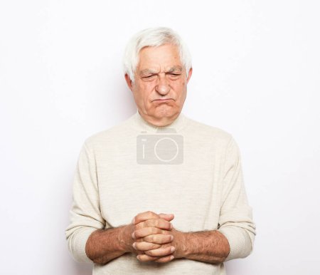 Téléchargez les photos : Homme âgé aux cheveux gris fronce les sourcils et semble mécontent sur fond blanc. Gros plan. - en image libre de droit