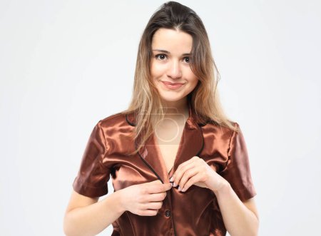 Foto de Estilo de vida, emoción, moda y concepto de la gente: hermosa joven con el pelo largo vestido con pijama marrón - Imagen libre de derechos