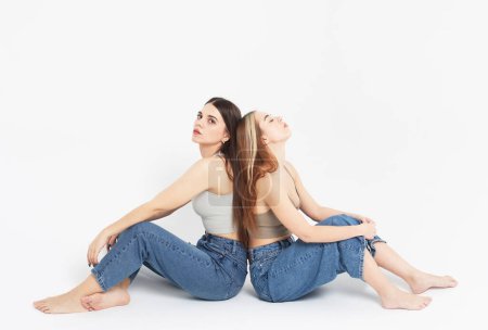 Foto de Estilo de vida, la moda y el concepto de la gente: Dos jóvenes amigas sentadas en el suelo juntas. - Imagen libre de derechos