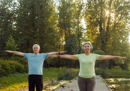 Téléchargez les photos : Belle forme active couple de personnes âgées famille pratiquant le yoga partenaire à l'extérieur dans la nature. - en image libre de droit