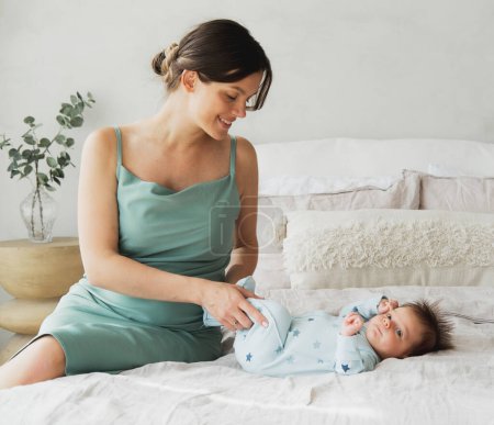 Foto de Retrato casero de un bebé recién nacido con madre en la cama. Madre abrazando a su pequeño hijo de 1 mes. - Imagen libre de derechos