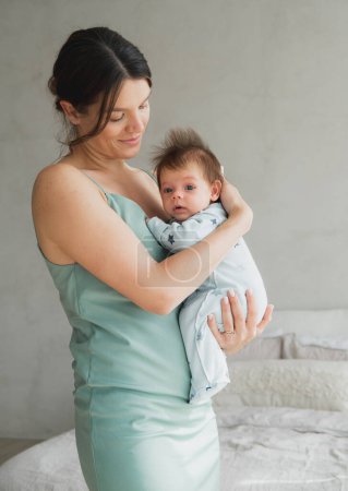 Téléchargez les photos : Maman aimante portant son nouveau-né à la maison. Portrait lumineux de maman heureuse tenant bébé endormi sur les mains. Mère étreignant son petit fils de 1 mois. - en image libre de droit