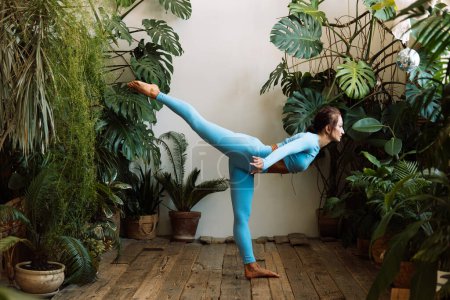 Téléchargez les photos : Une femme brune pratique le yoga dans la jungle urbaine. Femme en yoga asanas et Pilates à la maison. - en image libre de droit