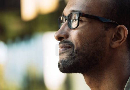 Téléchargez les photos : Un jeune afro-américain souriant non rasé portant des lunettes dans la rue. Portrait extérieur. - en image libre de droit
