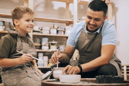 Photo for A young father and his seven-year-old son are engaged in creativity in a pottery workshop. Happy moments of joint activities with your child. Teaching creativity. - Royalty Free Image