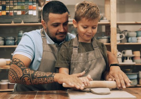Photo for Pottering with son. Confident young man and little boy making ceramic pot on the pottery class. Lifestyle and people concept. - Royalty Free Image