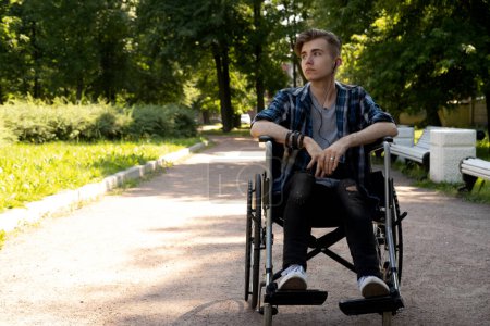Foto de Joven discapacitado en silla de ruedas caminar parque y escuchar música, día de verano - Imagen libre de derechos