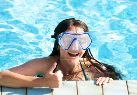 Téléchargez les photos : Jeune femme brune portant un masque de natation relaxant dans une piscine en été - en image libre de droit