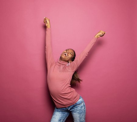Foto de Mujer afroamericana baila despreocupada, celebra la victoria y el éxito, se siente animada y enérgica - Imagen libre de derechos