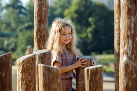 Foto de Niña feliz jugando en el patio de madera de los niños en el parque - Imagen libre de derechos