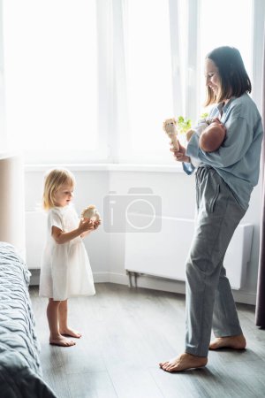 Téléchargez les photos : Une jeune mère avec un enfant dans les bras, à côté d'une fille de deux ans, sœur. Amour et tendresse. Une famille heureuse à la maison. - en image libre de droit