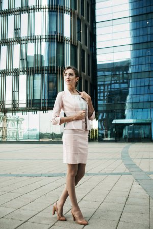 Téléchargez les photos : Belle jeune femme d'affaires utilise un téléphone portable devant un centre d'affaires moderne - en image libre de droit