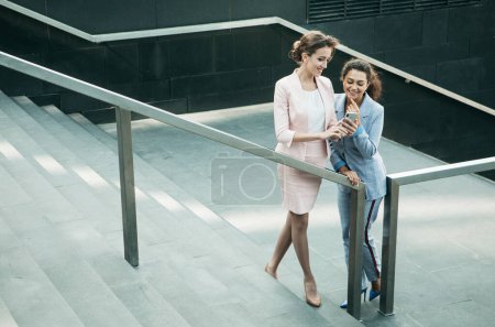 Téléchargez les photos : Business, people, tehnology et lifestyle concept : Deux femmes d'affaires avec mobile près des escaliers - en image libre de droit