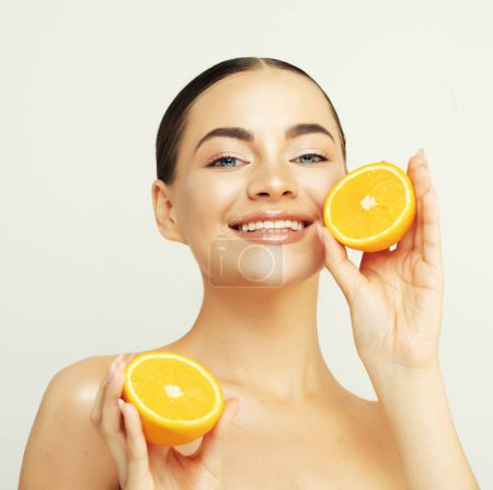 Photo for Beauty portrait of a lovely young woman standing isolated over white background, showing slices of an orange - Royalty Free Image